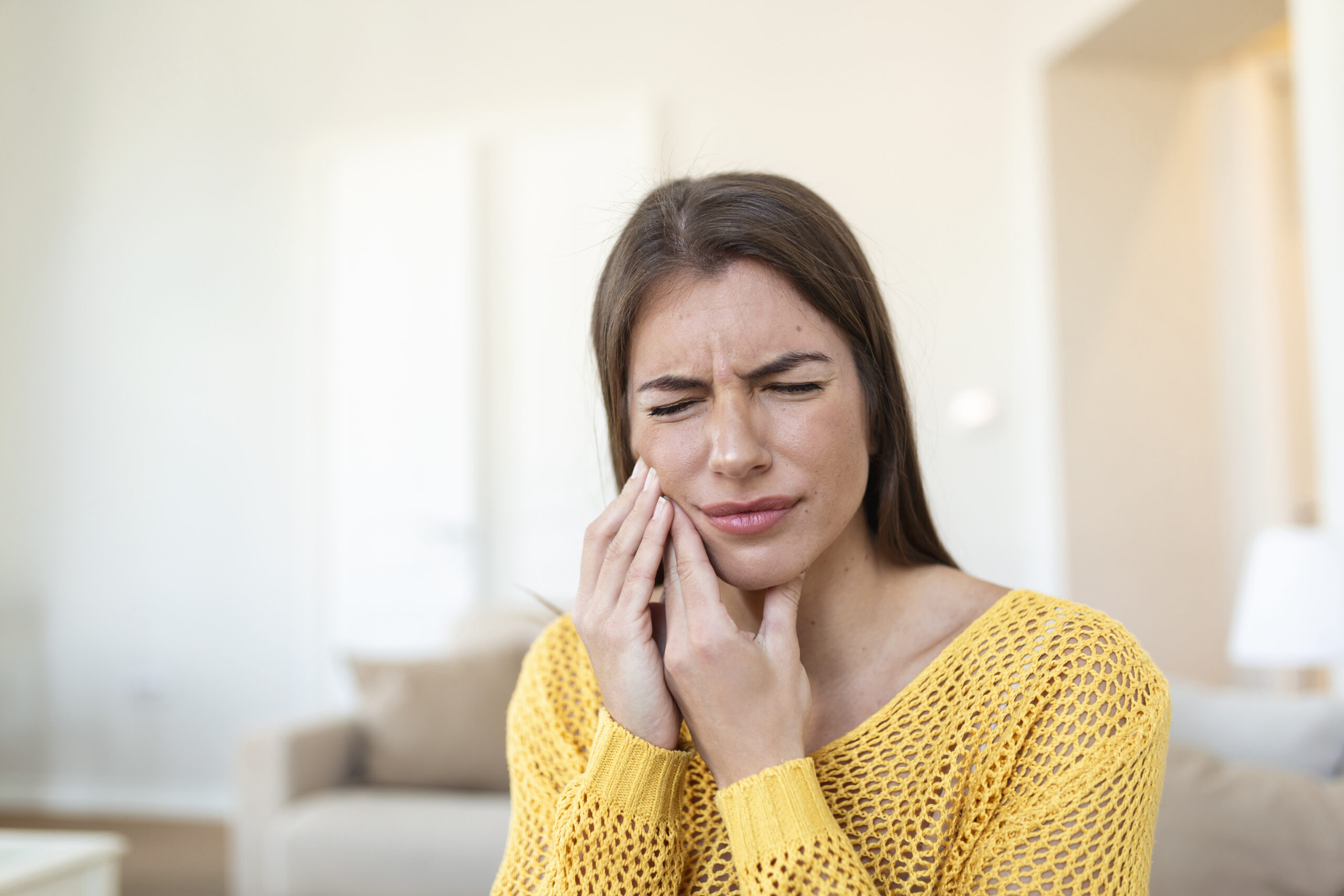 Ragazza con maglietta gialla che ha dolore ai denti per paradontite