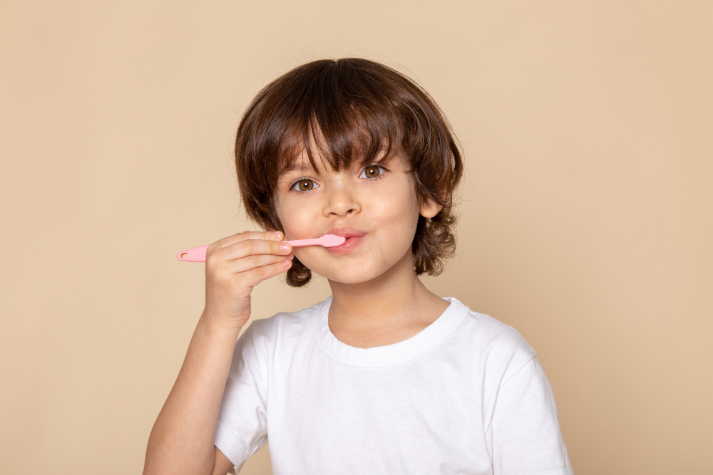 bambino in maglietta bianca con spazzolino rosa, prevenzione, igiene orale e cura denti da latte - orodent plus a Palermo